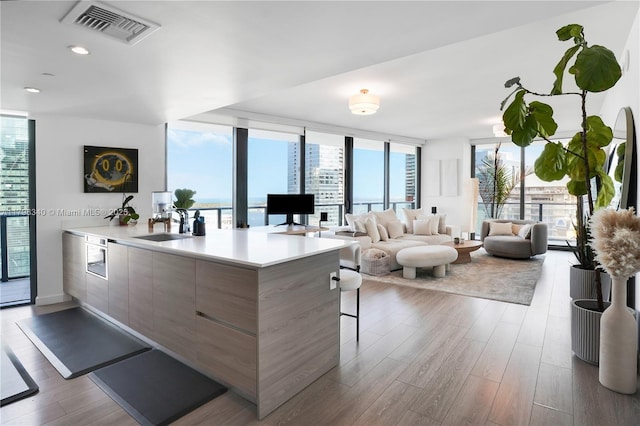 living room featuring dark wood-style flooring, a wall of windows, visible vents, and recessed lighting