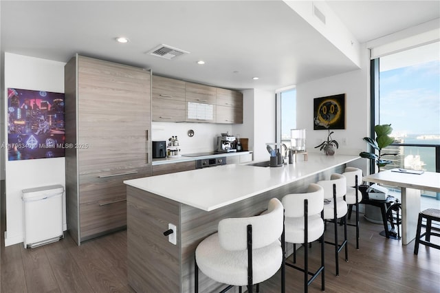 kitchen with a kitchen bar, a sink, visible vents, modern cabinets, and light countertops