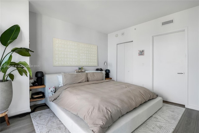 bedroom with a closet, visible vents, and wood finished floors