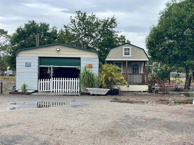 493 Camino Real Blvd, Clewiston, FL 33440 - view of front of property featuring a gambrel roof, covered porch, fence, and a garage