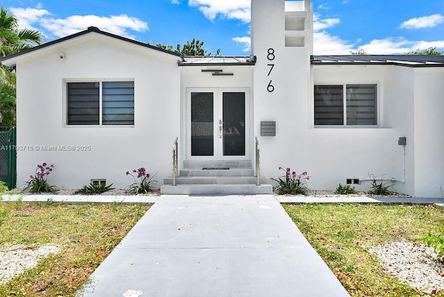 entrance to property with stucco siding, crawl space, metal roof, and a standing seam roof
