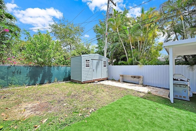 view of yard featuring an outdoor structure, a fenced backyard, and a shed