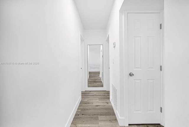 hallway featuring baseboards and light wood-type flooring