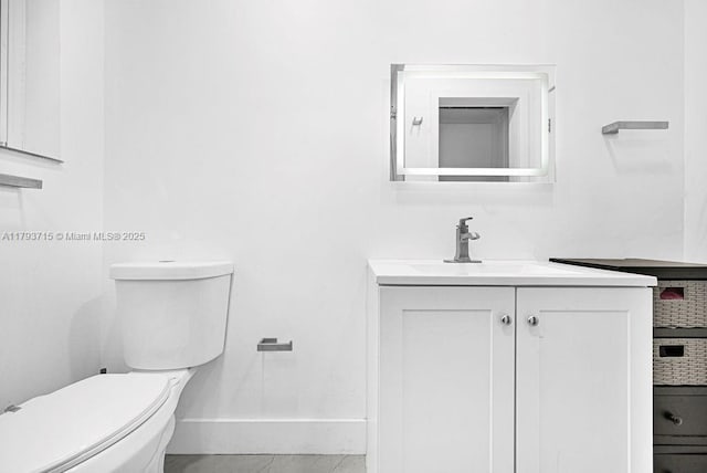 half bath with vanity, toilet, and baseboards