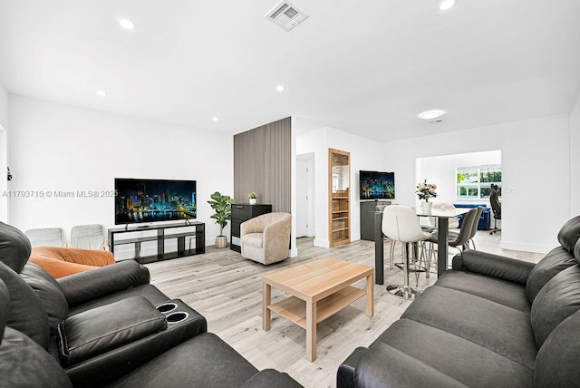 living room featuring baseboards, light wood-type flooring, visible vents, and recessed lighting
