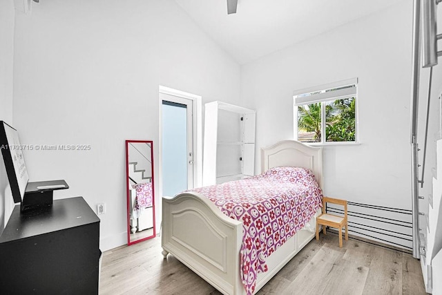 bedroom with a baseboard radiator, lofted ceiling, light wood-style flooring, and ceiling fan