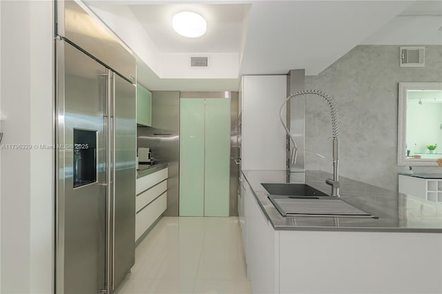 kitchen with high quality fridge, light tile patterned floors, visible vents, and stainless steel countertops
