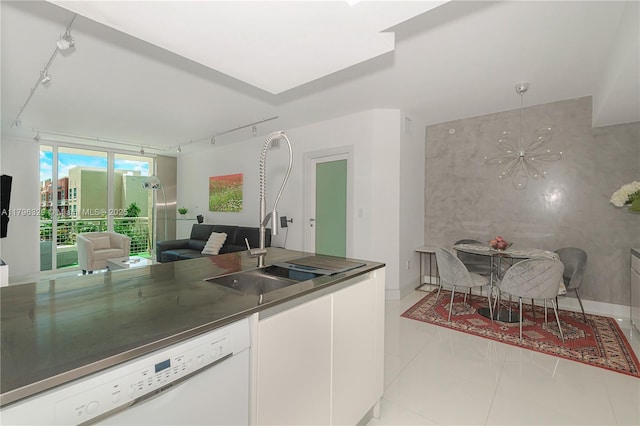 kitchen with rail lighting, dishwasher, a chandelier, open floor plan, and light tile patterned floors