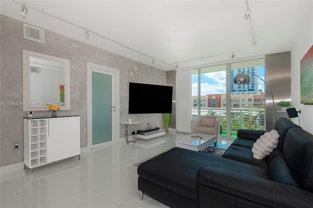 tiled living area featuring rail lighting, baseboards, visible vents, and wallpapered walls