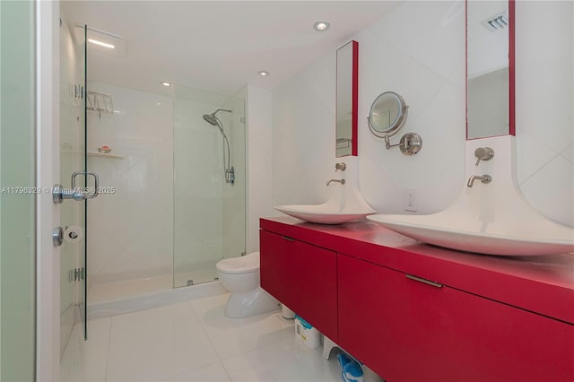 full bath with a sink, tile patterned flooring, toilet, and a stall shower