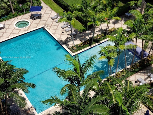 community pool with a patio area and a hot tub
