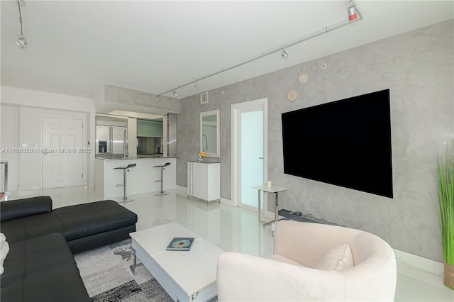 living area featuring rail lighting, baseboards, and visible vents