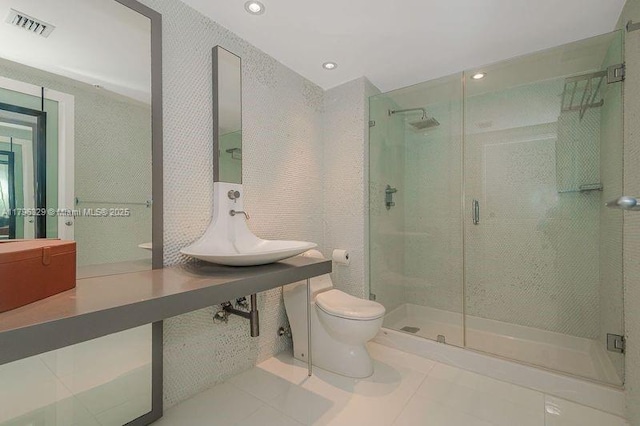 bathroom with toilet, a stall shower, a sink, visible vents, and tile patterned flooring