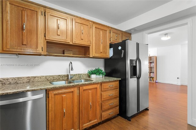 11 Island Ave Unit 407, Miami Beach, FL 33139 - kitchen featuring stainless steel appliances, a sink, wood finished floors, under cabinet range hood, and light stone countertops