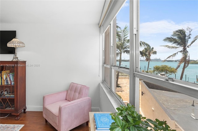 living area featuring a water view, wood finished floors, and baseboards