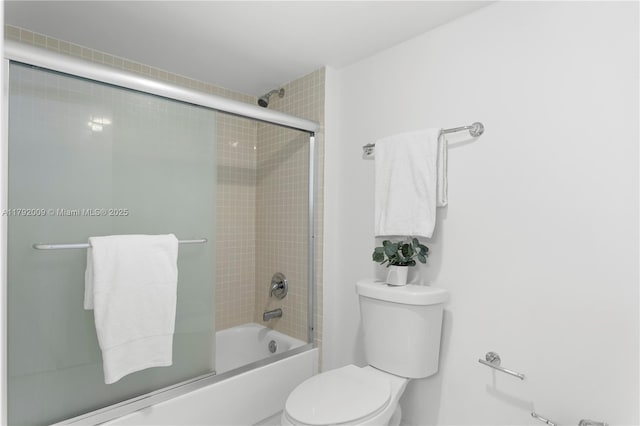 bathroom with toilet and shower / bath combination with glass door