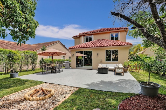rear view of property featuring a yard, an outdoor living space with a fire pit, stucco siding, and a tile roof