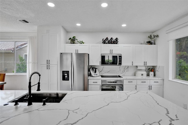 kitchen featuring stainless steel appliances, visible vents, a healthy amount of sunlight, and a sink