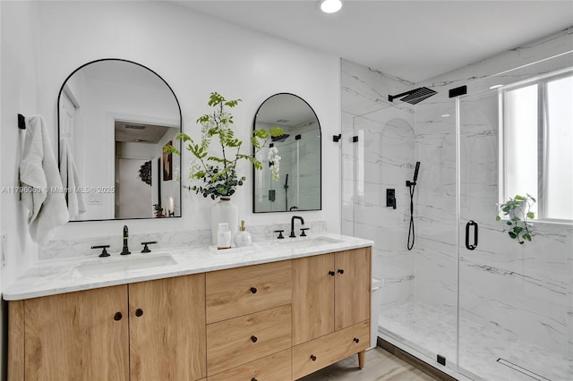 bathroom featuring a marble finish shower, a wealth of natural light, and a sink