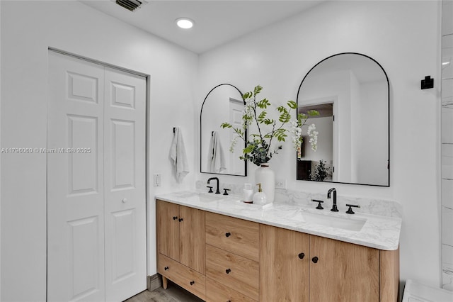 full bathroom with a closet, visible vents, double vanity, and a sink
