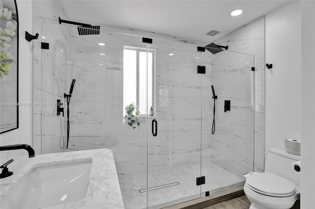 bathroom with toilet, a marble finish shower, a sink, visible vents, and recessed lighting