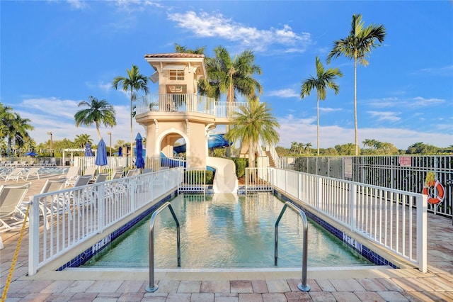 pool with a water slide, a patio area, and fence