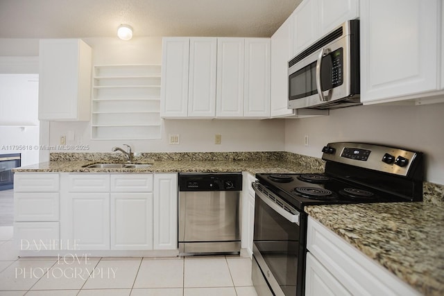 557 NW Fairfax Ave, Port St Lucie, FL 34983 - kitchen with light tile patterned flooring, a sink, open shelves, white cabinets, and appliances with stainless steel finishes