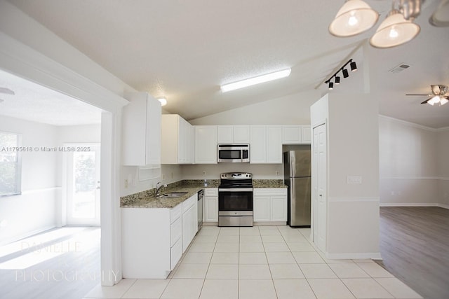 557 NW Fairfax Ave, Port St Lucie, FL 34983 - kitchen featuring stone counters, a sink, vaulted ceiling, white cabinets, and appliances with stainless steel finishes