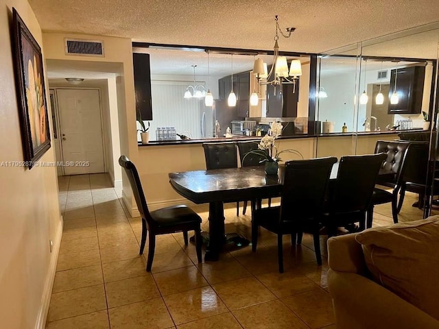 dining area featuring a chandelier, a textured ceiling, baseboards, and visible vents