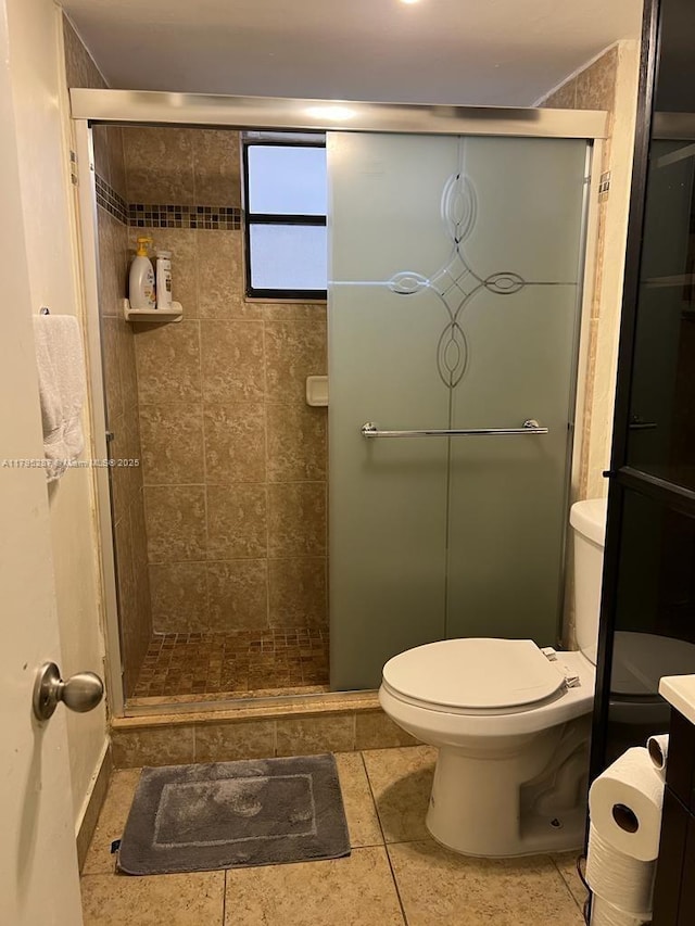 full bath featuring tile patterned floors, toilet, and a stall shower