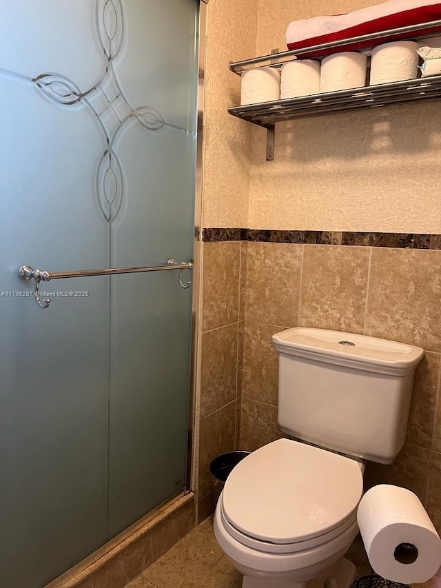 full bath featuring tile patterned floors, tile walls, toilet, and a stall shower