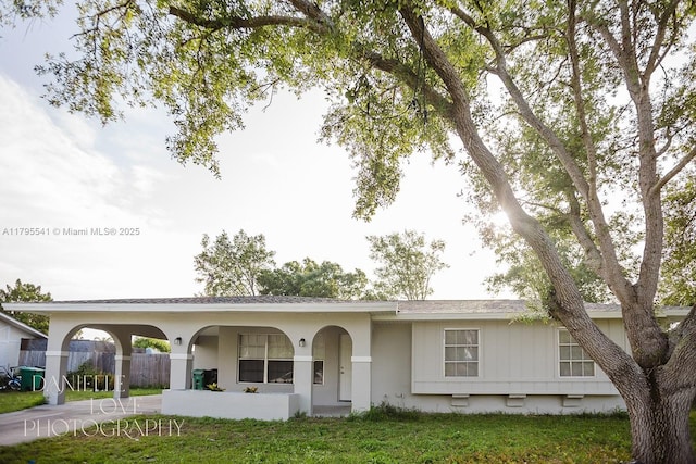 ranch-style home with a front lawn, concrete driveway, and fence