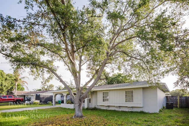 ranch-style house featuring cooling unit, driveway, a front lawn, and fence