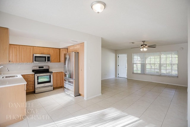 kitchen with light tile patterned floors, a sink, open floor plan, light countertops, and appliances with stainless steel finishes