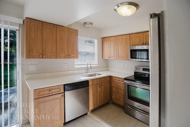 kitchen featuring a wealth of natural light, stainless steel appliances, light tile patterned flooring, and a sink
