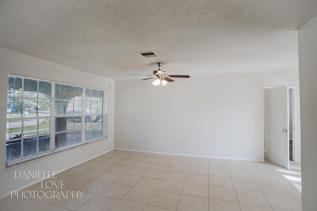 unfurnished room featuring a textured ceiling, baseboards, visible vents, ceiling fan, and light tile patterned flooring