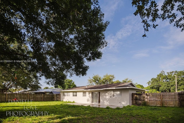 back of house featuring stucco siding, a lawn, and a fenced backyard