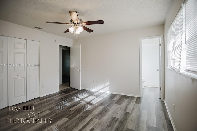 unfurnished bedroom with a closet, a textured ceiling, visible vents, and wood finished floors