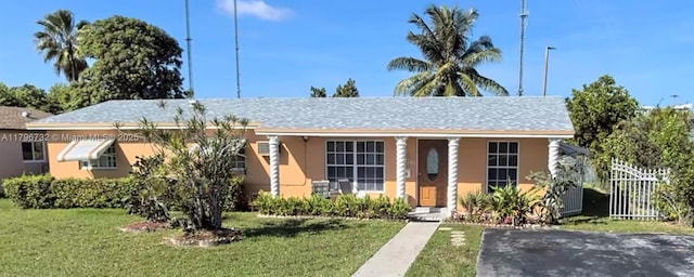 view of front facade featuring covered porch, stucco siding, fence, and a front lawn