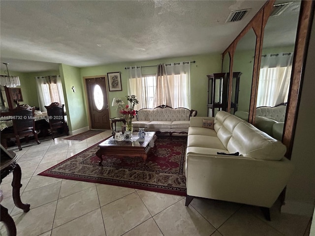 living area featuring a textured ceiling, visible vents, and tile patterned floors