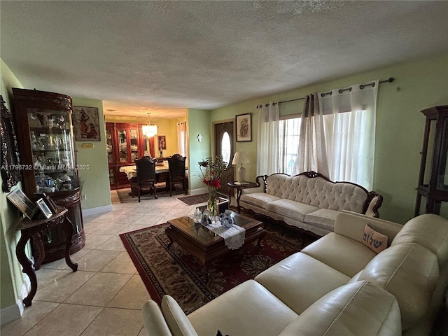 living room with light tile patterned floors, a notable chandelier, a textured ceiling, and baseboards