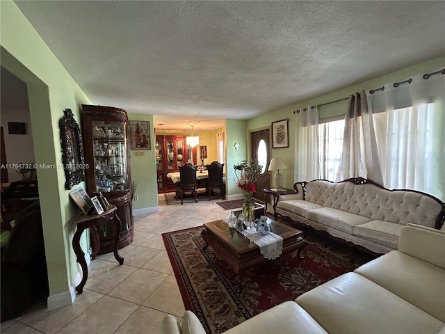 living area featuring an inviting chandelier, a textured ceiling, baseboards, and light tile patterned floors
