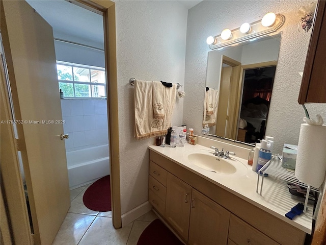 full bathroom featuring tile patterned flooring, a textured wall, a bathtub, and vanity