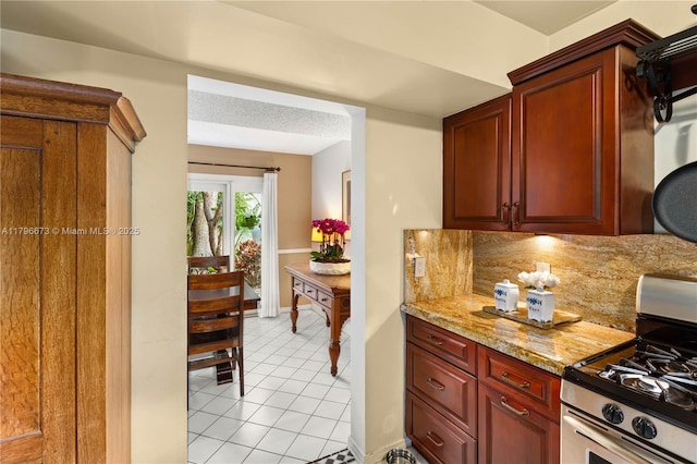 9033 SW 78th Pl, Miami, FL 33156 - kitchen with stainless steel gas range, light tile patterned floors, light stone counters, dark brown cabinets, and baseboards