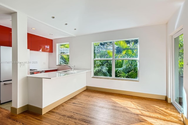 5812 Alton Rd, Miami Beach, FL 33140 - kitchen featuring freestanding refrigerator, baseboards, a peninsula, light countertops, and light wood-type flooring