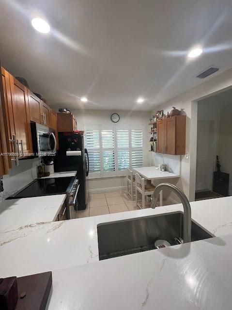 kitchen featuring appliances with stainless steel finishes, a sink, brown cabinets, recessed lighting, and open shelves