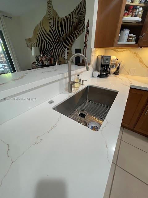 kitchen featuring a sink, light stone countertops, and tasteful backsplash