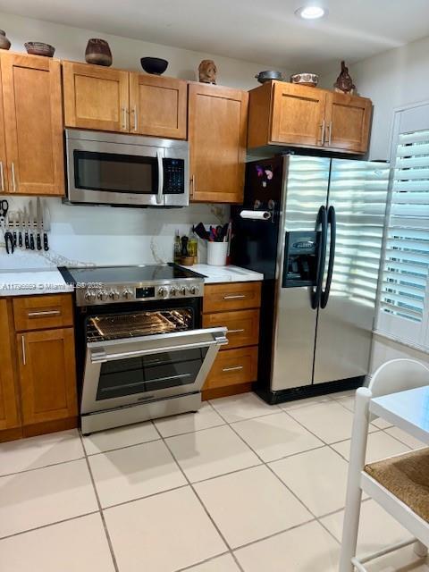 12815 SW 71st Ln, Miami, FL 33183 - kitchen featuring stainless steel appliances, brown cabinets, light countertops, light tile patterned floors, and recessed lighting