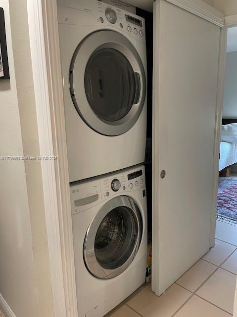 washroom with laundry area, light tile patterned flooring, and stacked washer / drying machine
