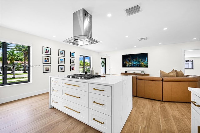 kitchen with stainless steel gas stovetop, visible vents, island exhaust hood, and light wood-style floors